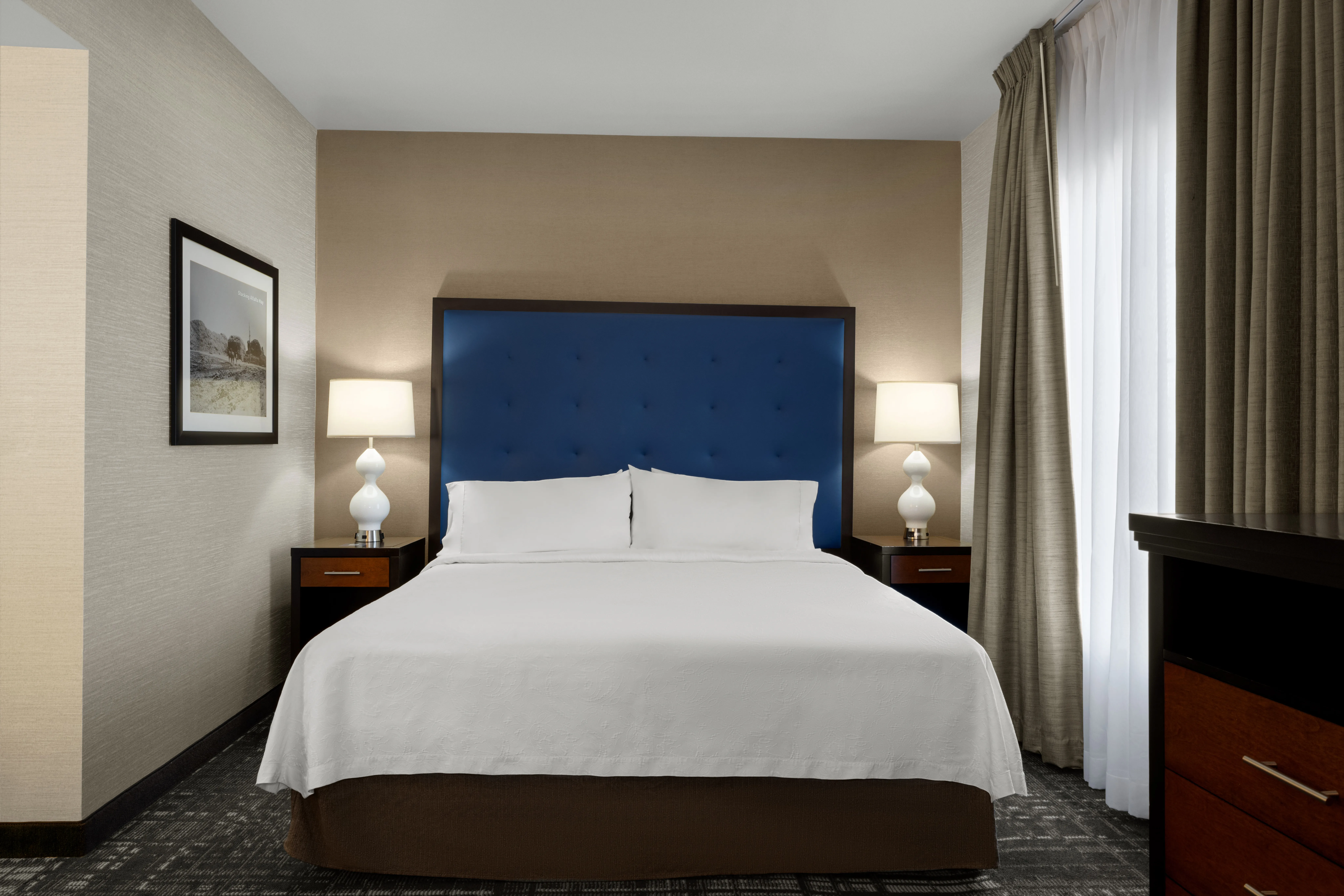 Hotel guest room with a neatly made king bed and bedside lamps